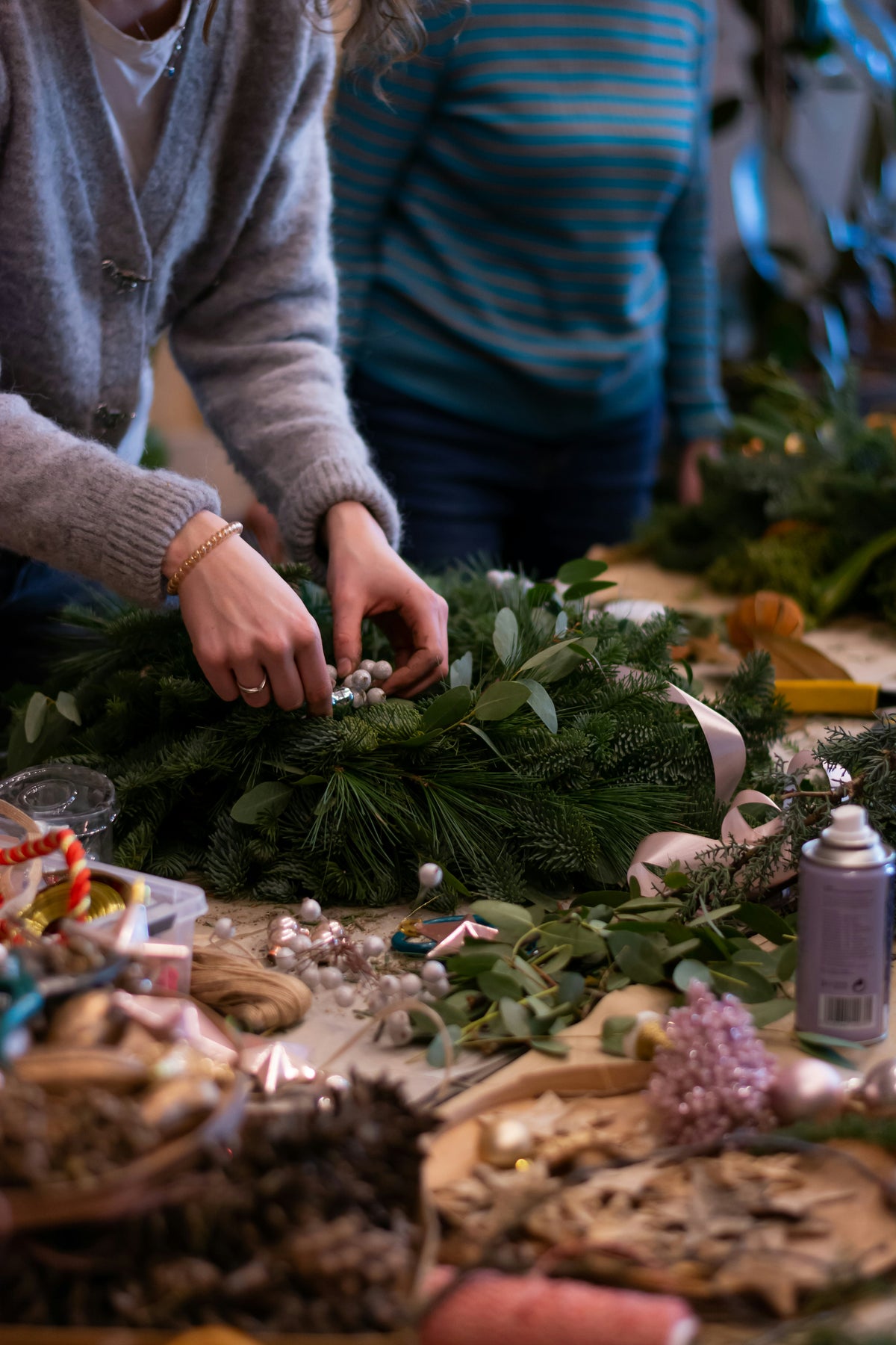 Frau bindet Adventskranz und dekoriert