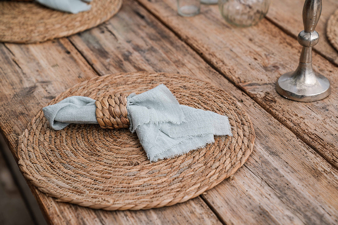 Serviette mit Serviettenring aus Rattan auf Tischset.