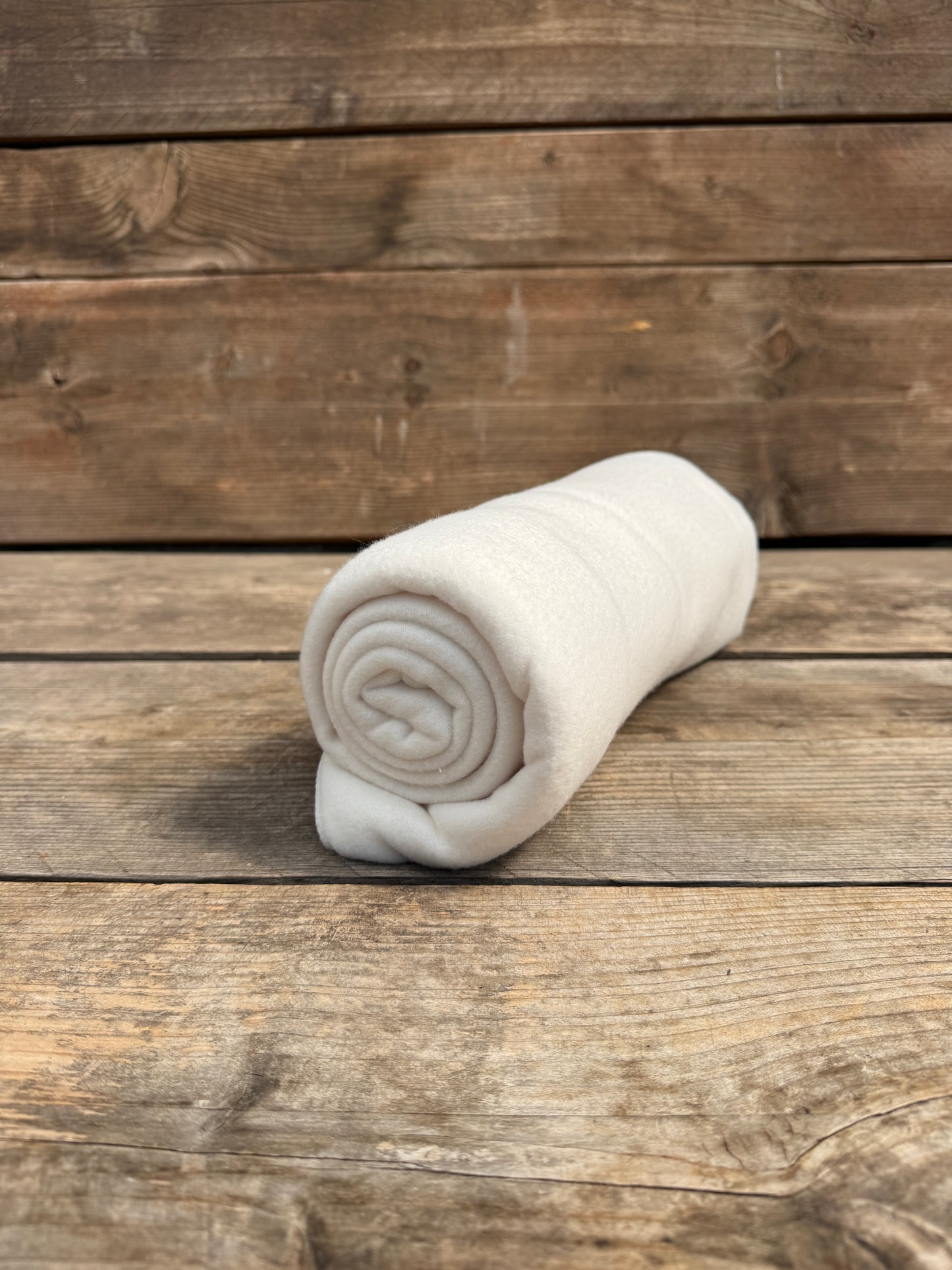 Fleece-Decke in weiß auf Holzbank