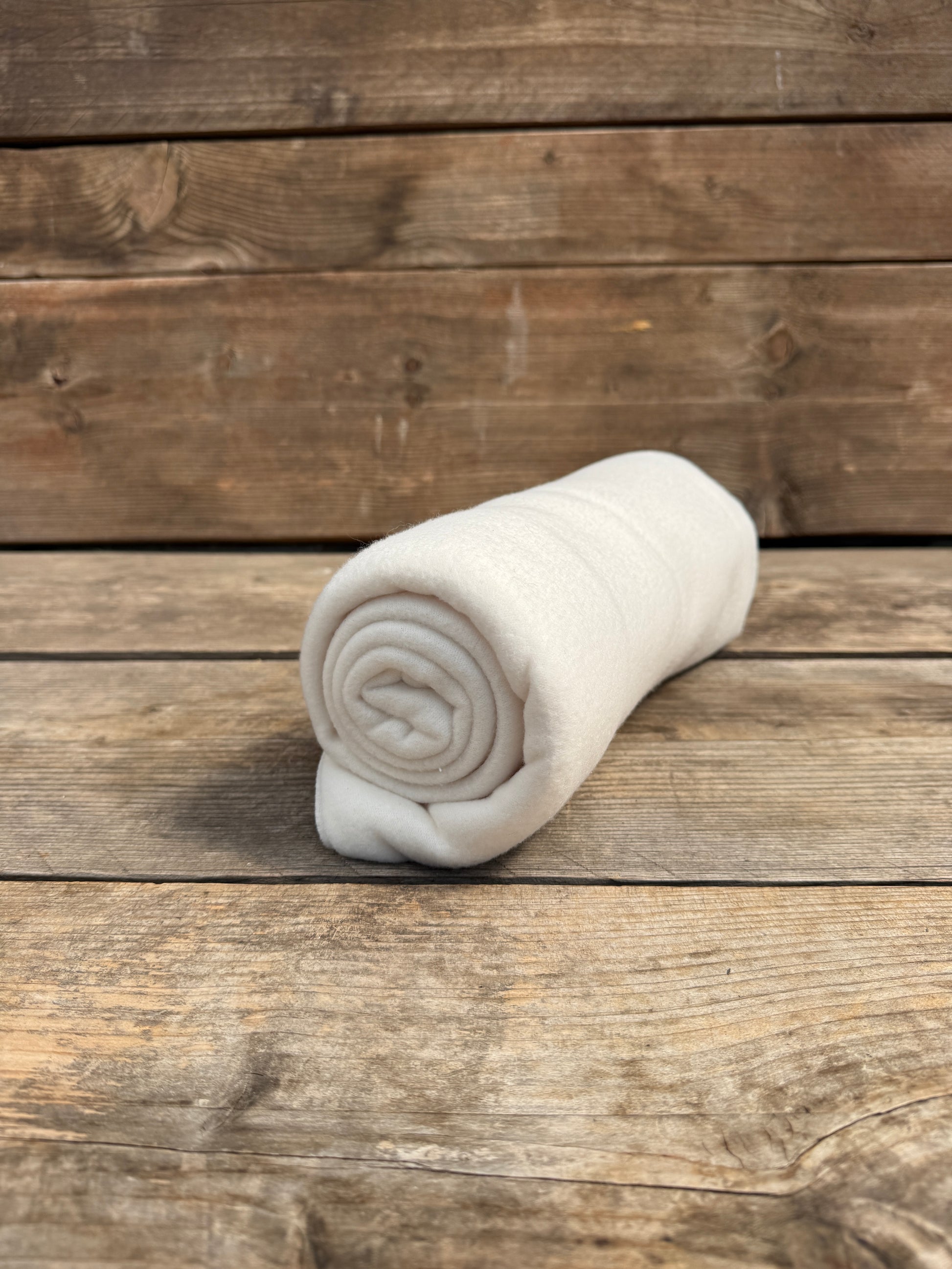 Fleece-Decke in weiß auf Holzbank