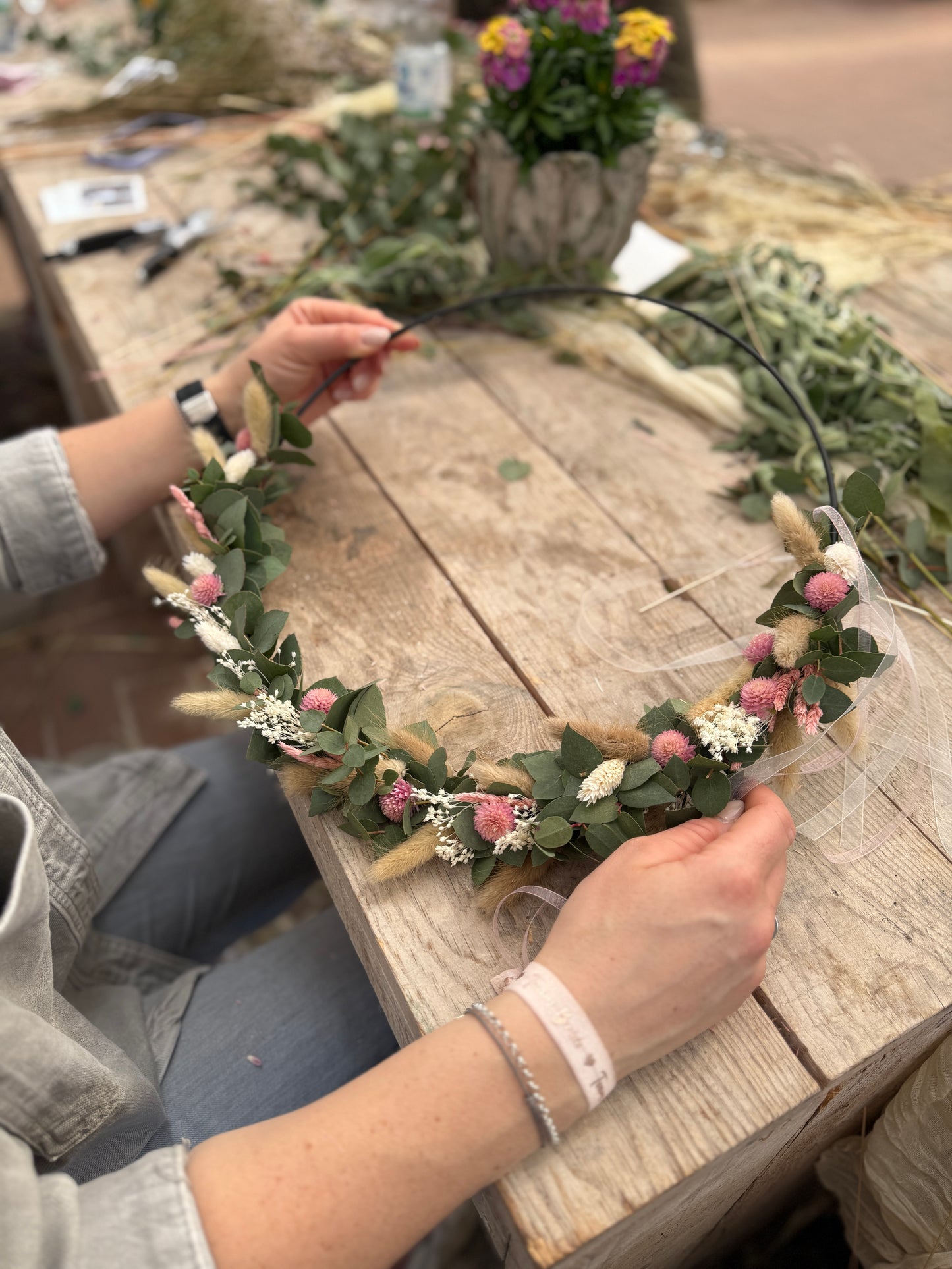 Frau hält Kranz aus Trockenblumen mit Metallring