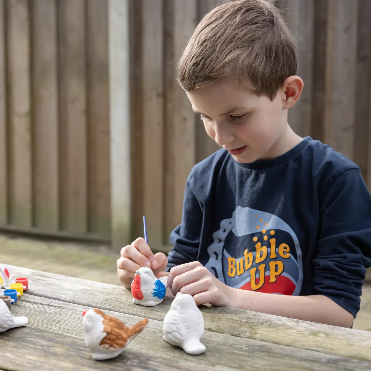 Kind bemalt Vogelfiguren mit Farbe und Pinsel