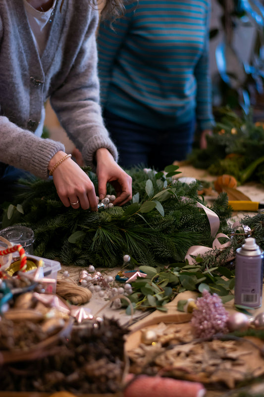 Frau bindet Adventskranz und dekoriert